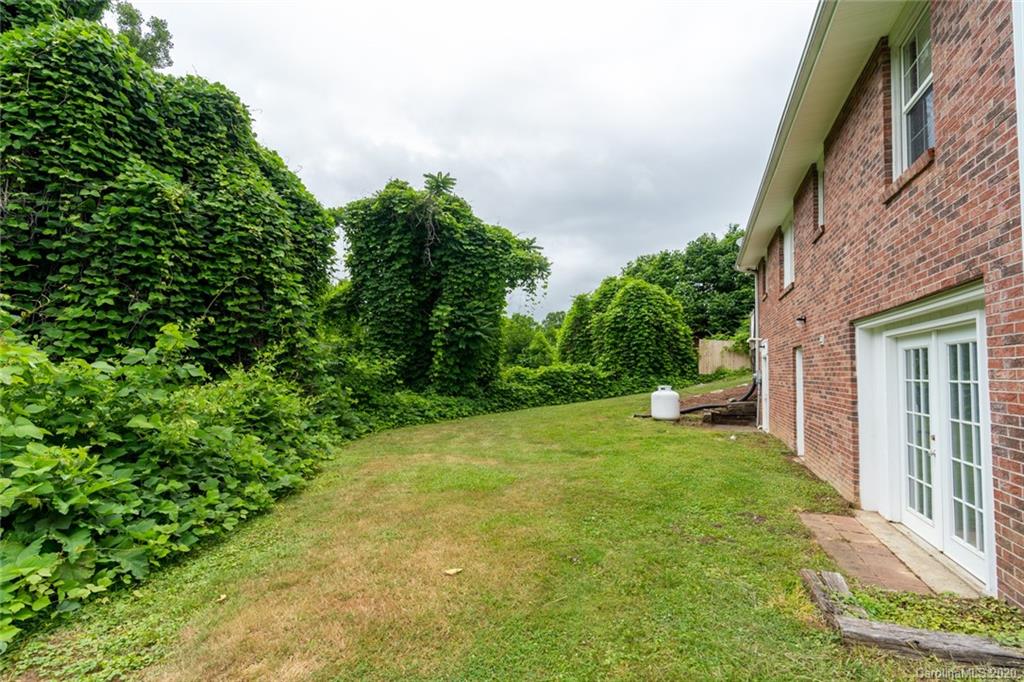 537 Souther Road Fletcher, NC 28732 - Photo 29 of 31 a backyard of a house with table and chairs plants and large trees
