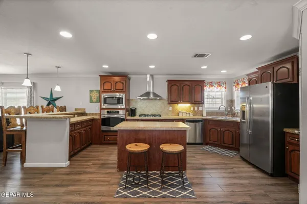 a kitchen with stainless steel appliances granite countertop a refrigerator a stove top oven and sink