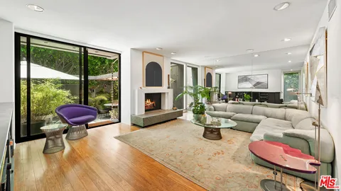 a living room with furniture a fireplace and a floor to ceiling window