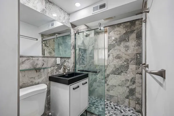 a bathroom with a granite countertop sink a toilet and shower