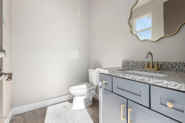 a bathroom with a granite countertop toilet sink and mirror