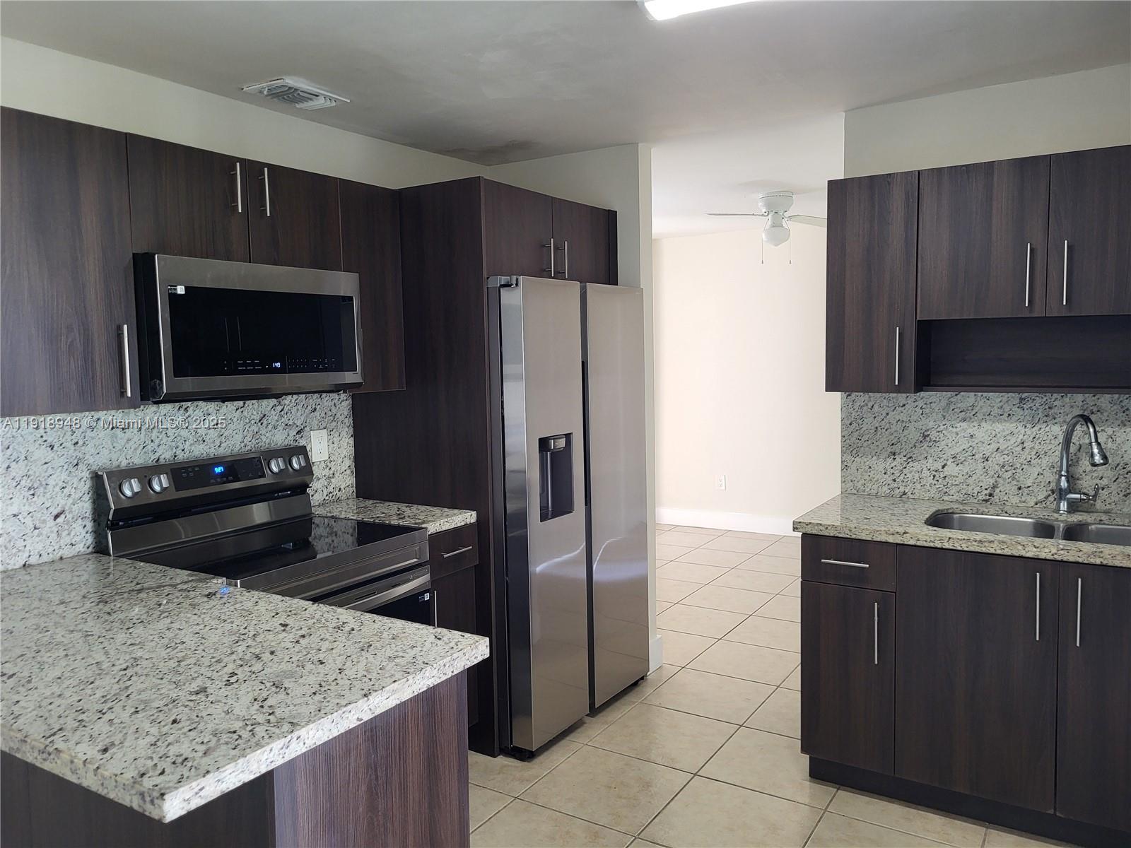 12309 Southwest 250th Street Homestead, FL 33032 - Photo 11 of 26 a kitchen with stainless steel appliances kitchen island granite countertop a refrigerator stove and microwave