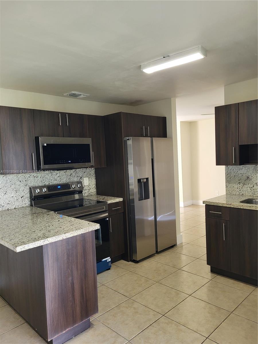 12309 Southwest 250th Street Homestead, FL 33032 - Photo 10 of 26 a kitchen with granite countertop a refrigerator and a stove top oven