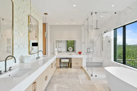 a large white bathroom with a tub sink shower and mirror