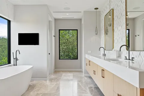 a spacious bathroom with a double vanity sink a mirror and a bathtub