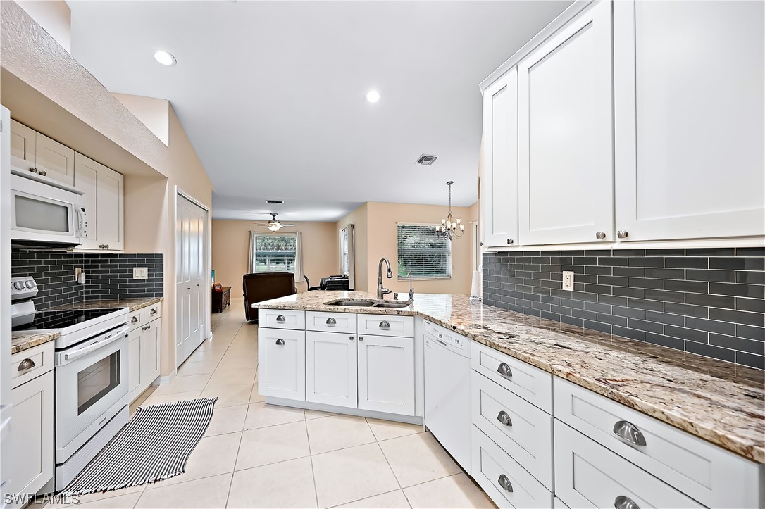 3535 18th Avenue Southeast Naples, FL 34117 - Photo 4 of 32 a large kitchen with stainless steel appliances granite countertop a stove sink and cabinets