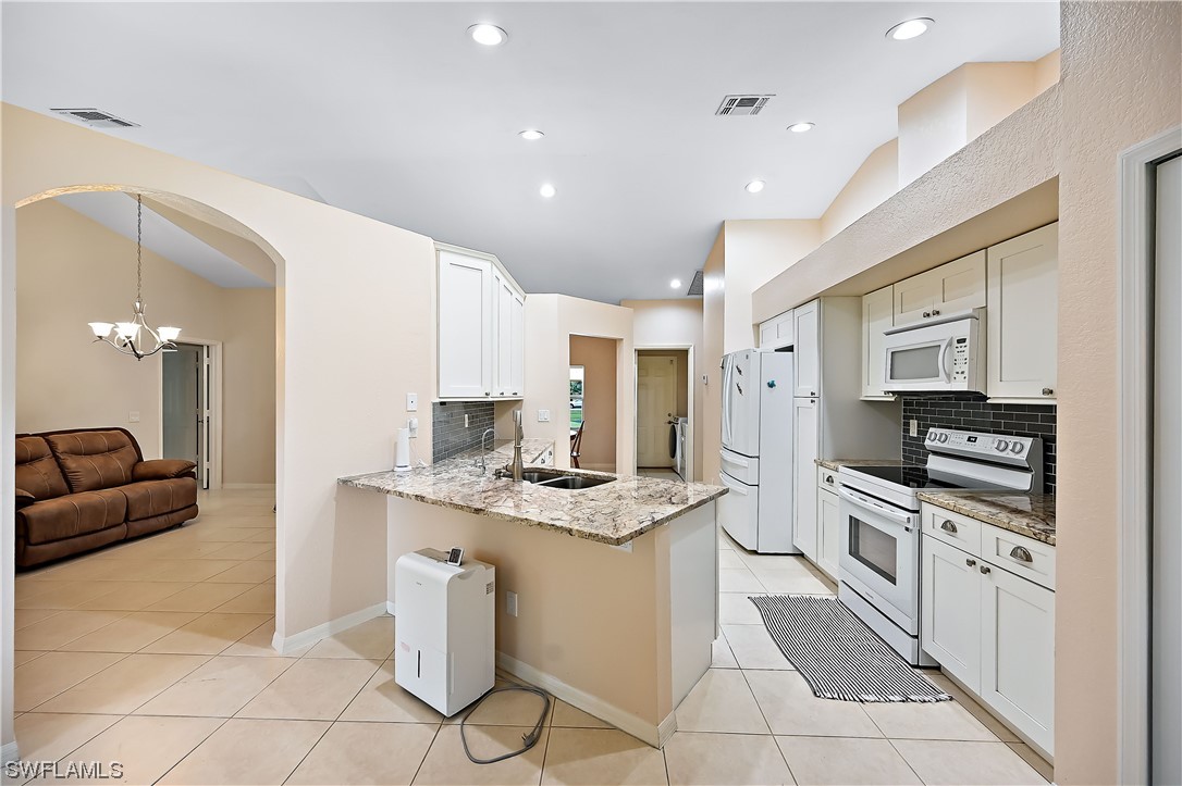 3535 18th Avenue Southeast Naples, FL 34117 - Photo 9 of 32 a kitchen with stainless steel appliances kitchen island granite countertop a stove a sink and a refrigerator