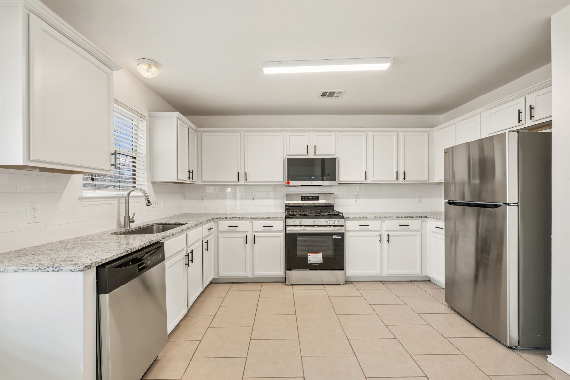 15216 Mandarin Crossing Pflugerville, TX 78660 - Photo 12 of 40 Kitchen with appliances with stainless steel finishes, white cabinets, and light stone counters
