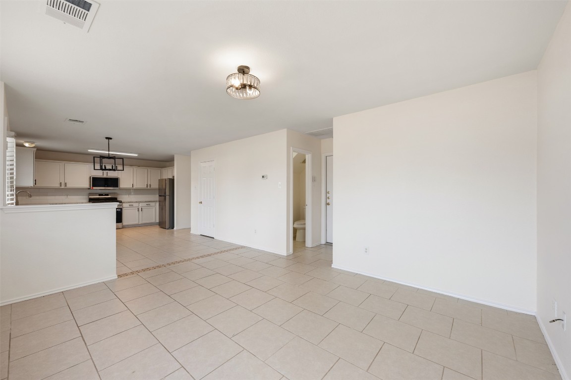 15216 Mandarin Crossing Pflugerville, TX 78660 - Photo 19 of 40 Unfurnished living room with light tile patterned floors and baseboards