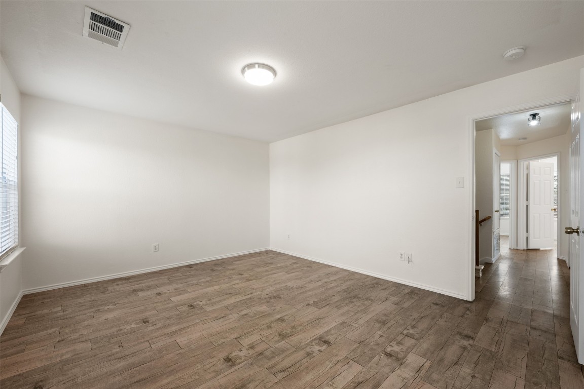 15216 Mandarin Crossing Pflugerville, TX 78660 - Photo 28 of 40 Empty room with healthy amount of natural light and dark wood-style flooring
