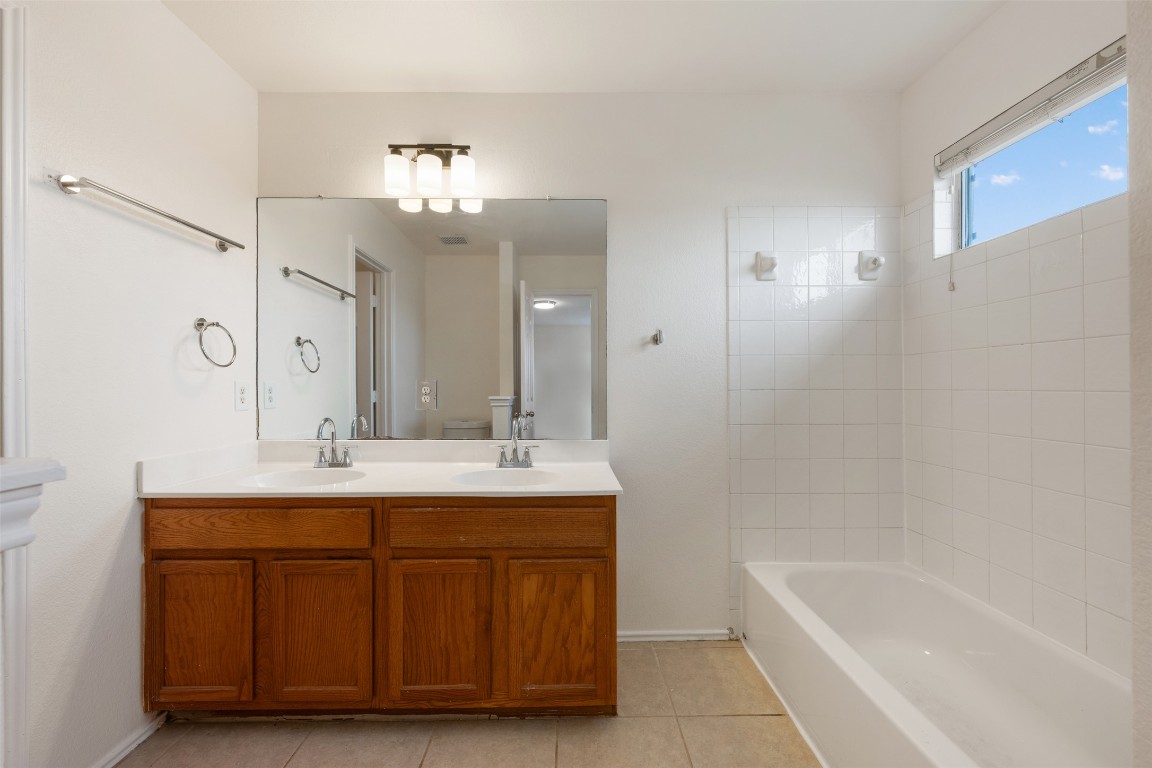 15216 Mandarin Crossing Pflugerville, TX 78660 - Photo 29 of 40 Full bath featuring double vanity, light tile patterned floors, and shower / tub combination