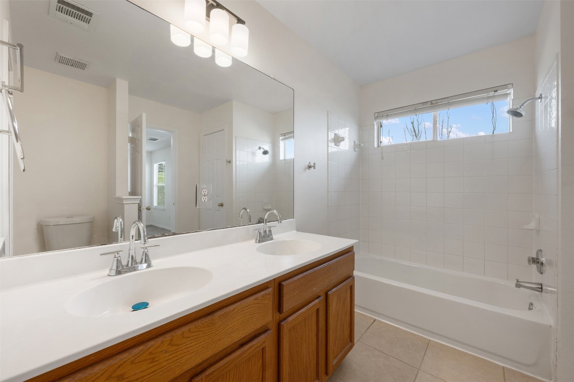 15216 Mandarin Crossing Pflugerville, TX 78660 - Photo 30 of 40 Full bathroom with double vanity, light tile patterned flooring, and shower / bathtub combination
