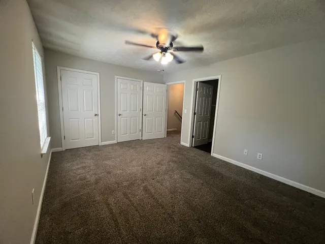 an empty room with closet and a ceiling fan