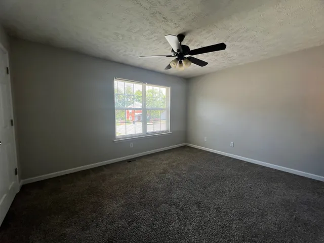 an empty room with windows and fan