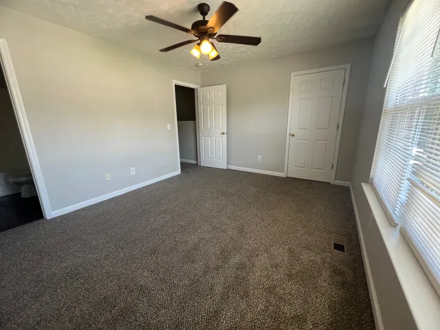 an empty room with windows and fan