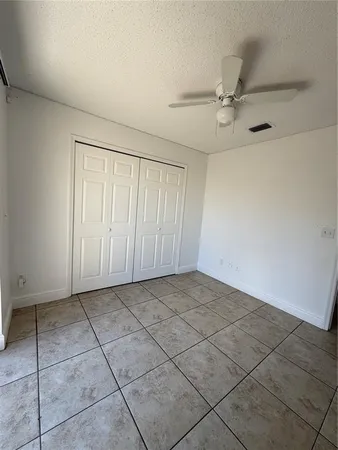 a view of an empty room and chandelier fan