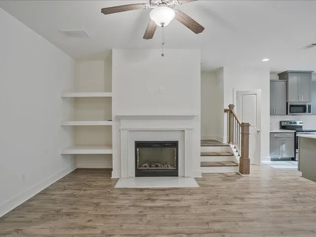a view of a livingroom with a fireplace a ceiling fan and windows