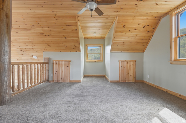 20 Q Puma Road Fairview, UT 84629 - Photo 17 of 27 Loft space featuring sloped wood-finish ceilings, wood-finish window frames, two windows, two wood-finish storage access doors, and soft gray carpeting