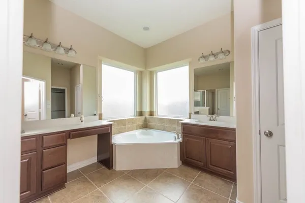 a large white bathroom with a tub sink and mirror