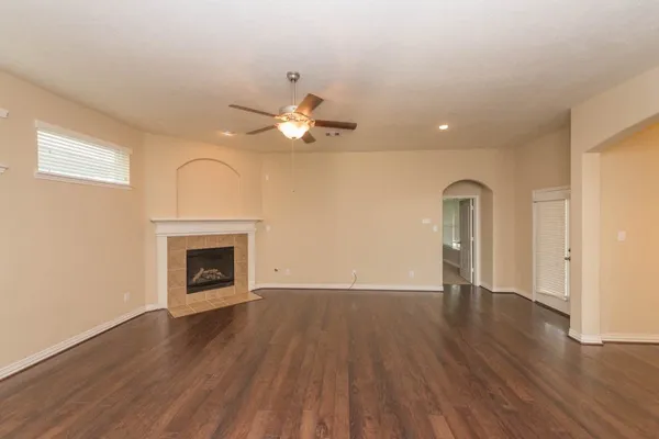 an empty room with wooden floor fan and window