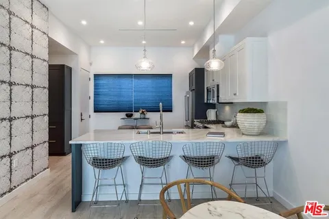 a kitchen with stainless steel appliances granite countertop a table chairs sink refrigerator and microwave