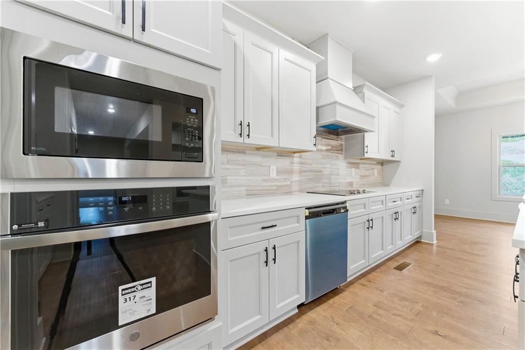 158 Races Road Hoschton, GA 30548 - Photo 9 of 24 a kitchen with white cabinets a sink and a stove with wooden floor