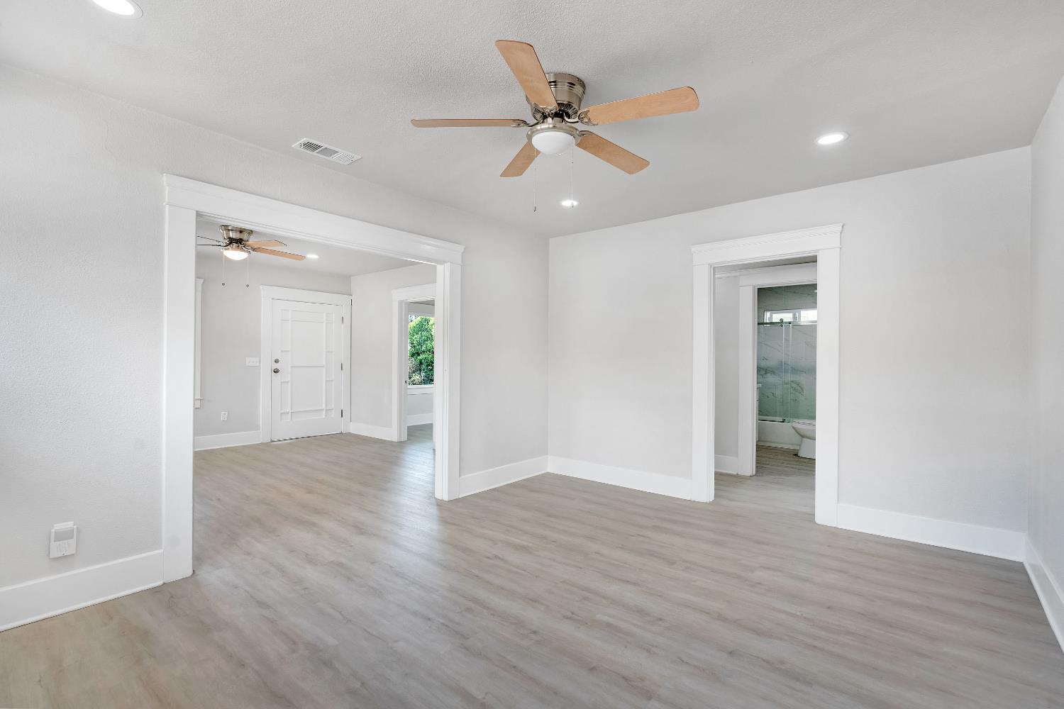 3935 East Balch Avenue Fresno, CA 93702 - Photo 11 of 25 an empty room with wooden floor a ceiling fan and windows
