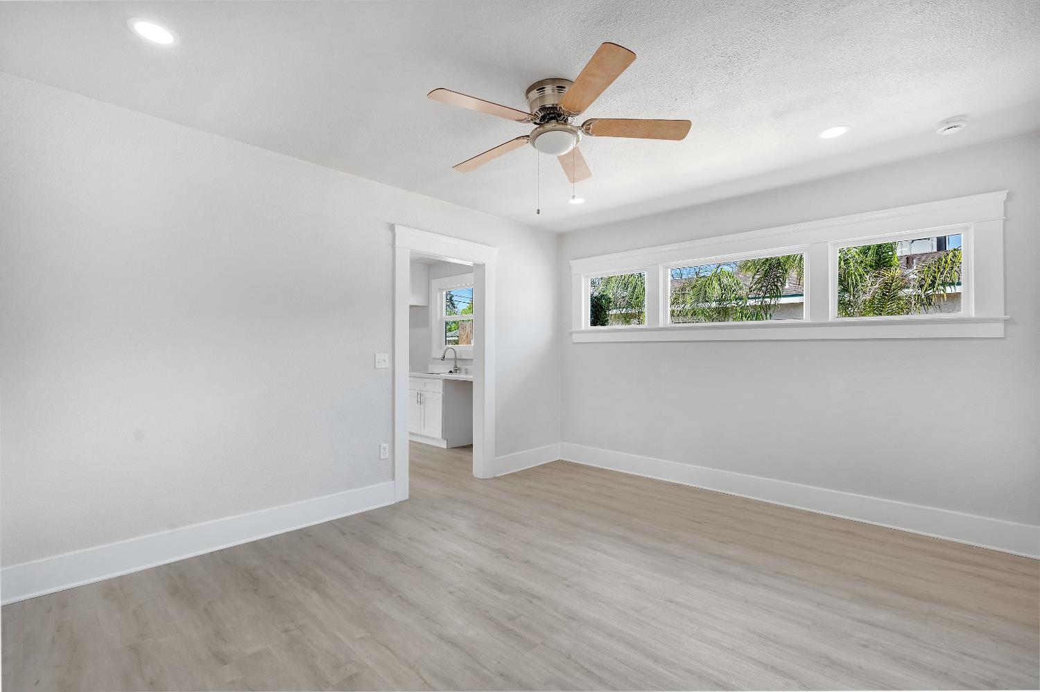 3935 East Balch Avenue Fresno, CA 93702 - Photo 9 of 25 an empty room with wooden floor ceiling fan and windows