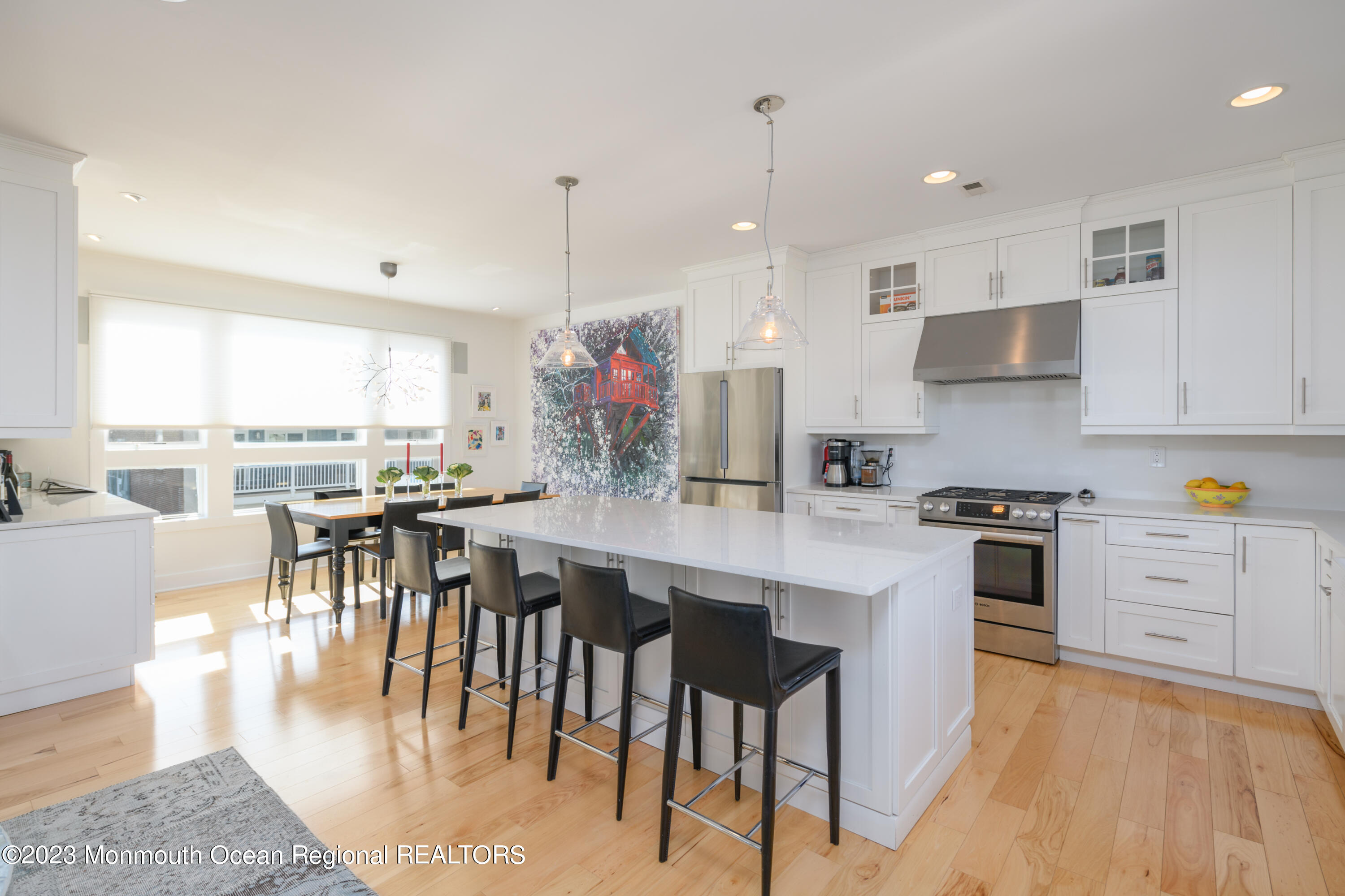25 Village Road Sea Bright, NJ 07760 - Photo 23 of 37 a kitchen with stainless steel appliances granite countertop a stove a refrigerator a kitchen island a dining table and chairs with wooden floor