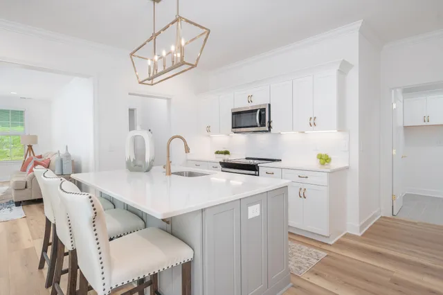 a kitchen with stainless steel appliances kitchen island a table chairs sink and cabinets