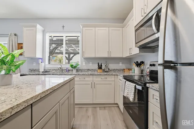 a kitchen with stainless steel appliances granite countertop a stove top oven a sink dishwasher a dining table and chairs with wooden floor