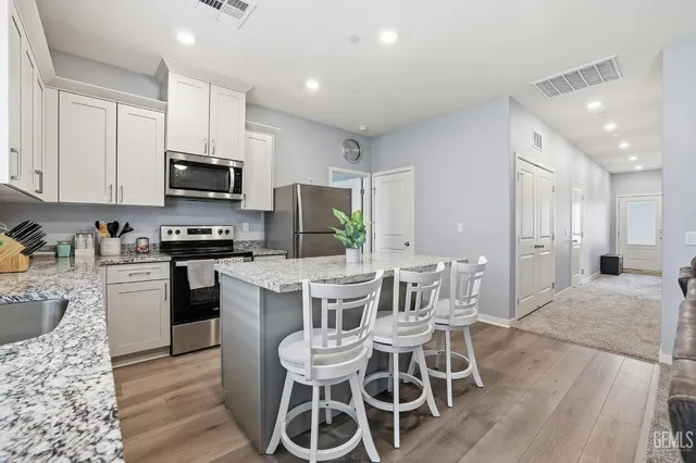 a kitchen with stainless steel appliances granite countertop a white cabinets and a refrigerator