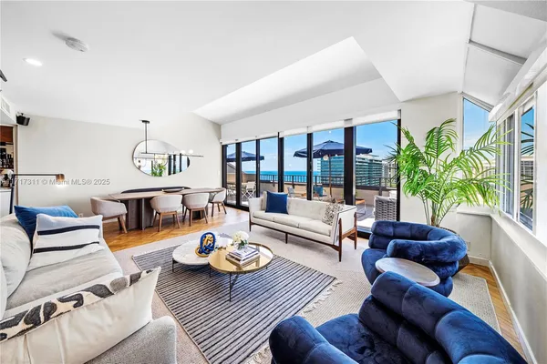 a living room with furniture wooden floor and floor to ceiling windows