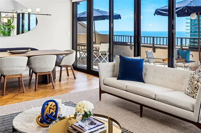 a view of a patio with couches table and chairs under an umbrella with wooden floor
