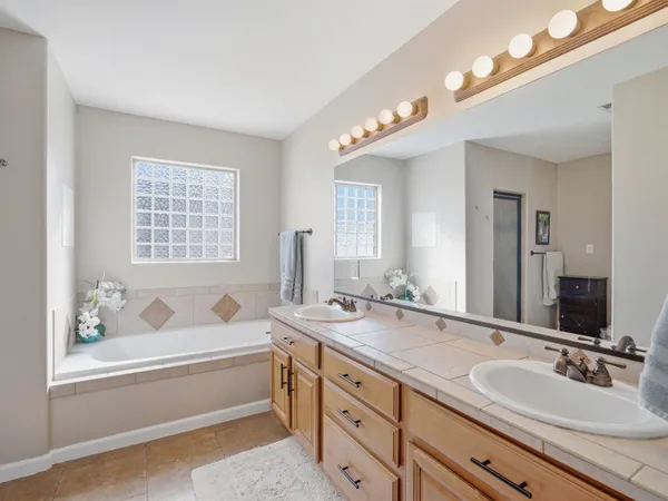a bathroom with a tub a sink and a large mirror
