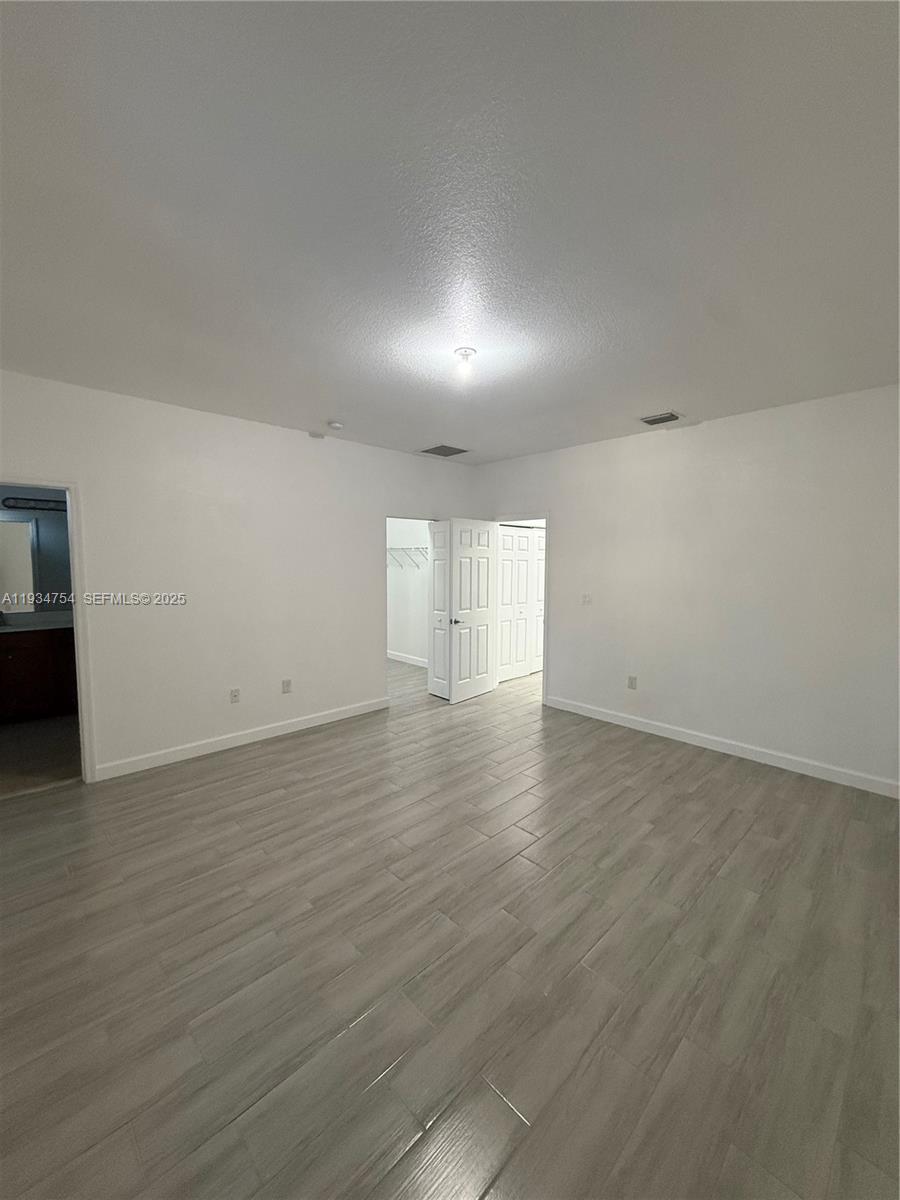 9248 Southwest 170th Place, Unit 9248 Miami, FL 33196 - Photo 19 of 30 an empty room with wooden floor and windows