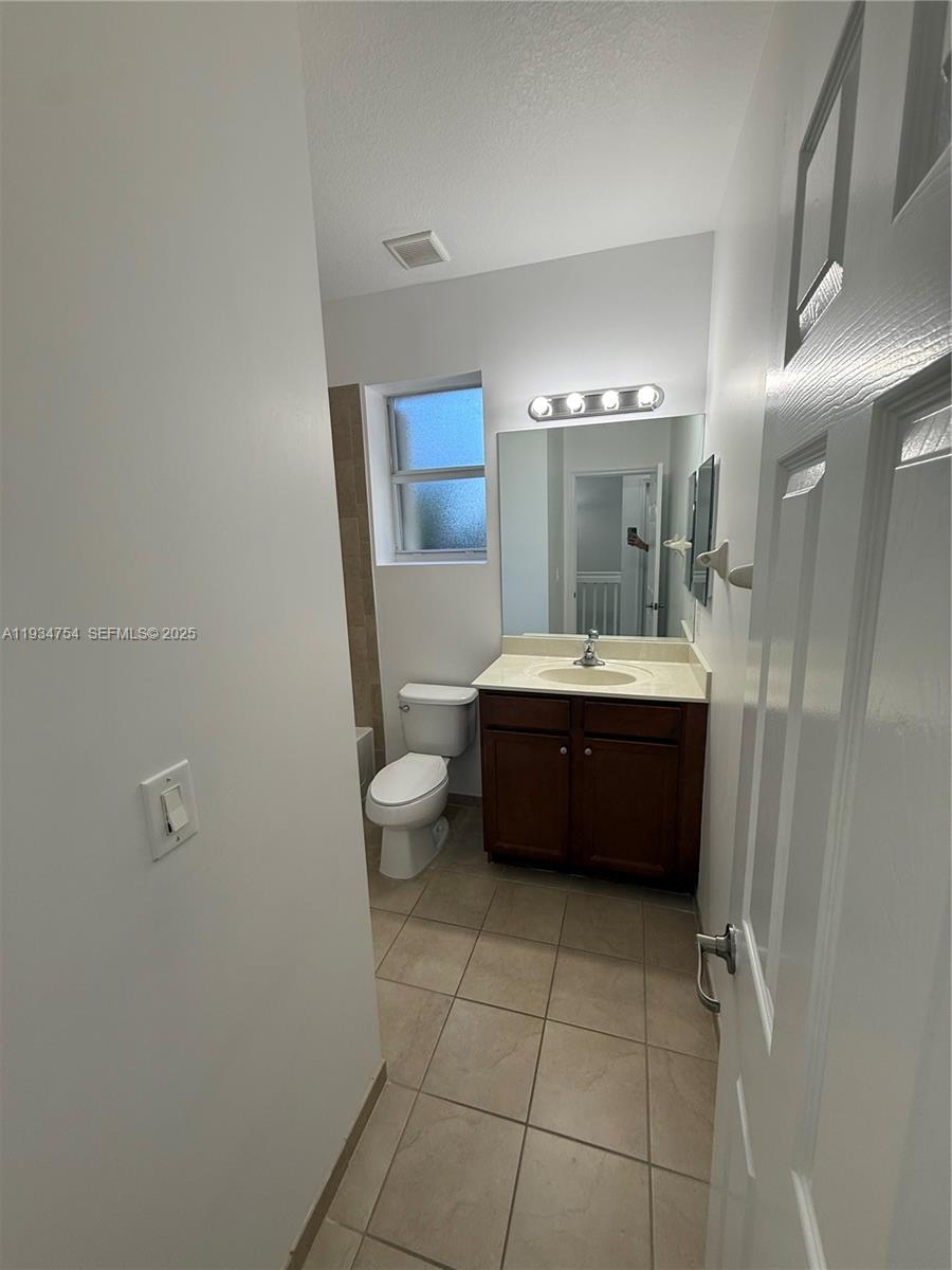 9248 Southwest 170th Place, Unit 9248 Miami, FL 33196 - Photo 24 of 30 a bathroom with a sink a mirror and a toilet
