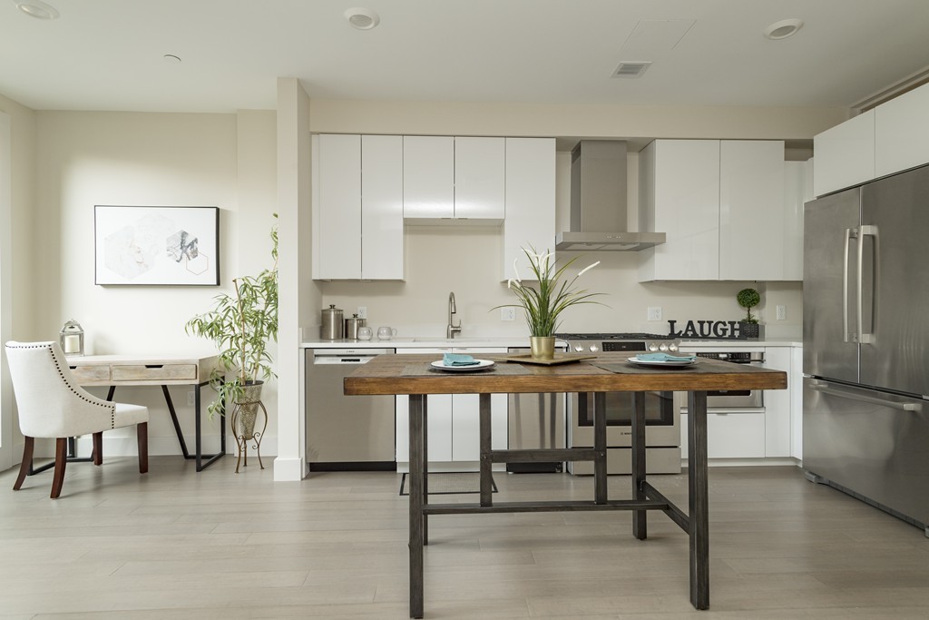 121 Portland Street, Unit 703 Boston, MA 02114 - Photo 1 of 13 a kitchen with stainless steel appliances a table chairs refrigerator and cabinets