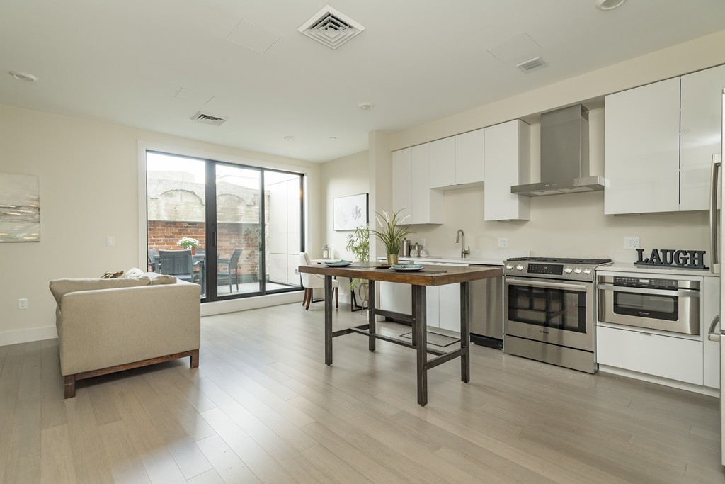 121 Portland Street, Unit 703 Boston, MA 02114 - Photo 2 of 13 a kitchen with a stove a sink a refrigerator and white cabinets with wooden floor