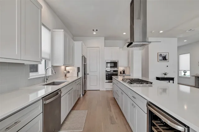 a large kitchen with stainless steel appliances a sink a stove and a refrigerator