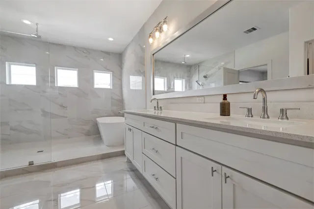 a spacious bathroom with double sink a toilet a mirror and shower