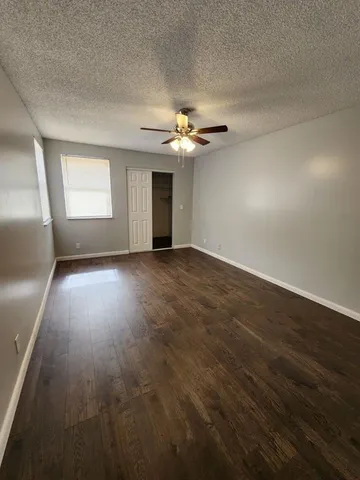 an empty room with wooden floor chandelier fan and windows