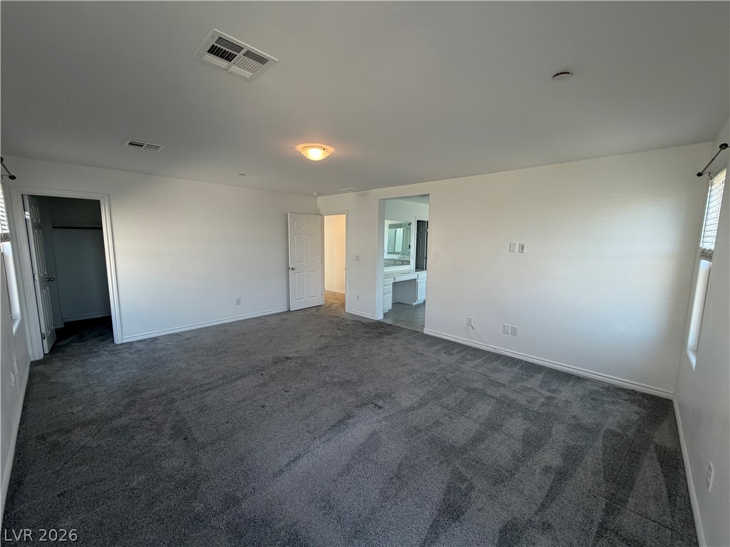 3228 Azalea Ridge Court Henderson, NV 89052 - Photo 8 of 28 A spacious primary bedroom with plush carpeting offers direct access to an en-suite bath.