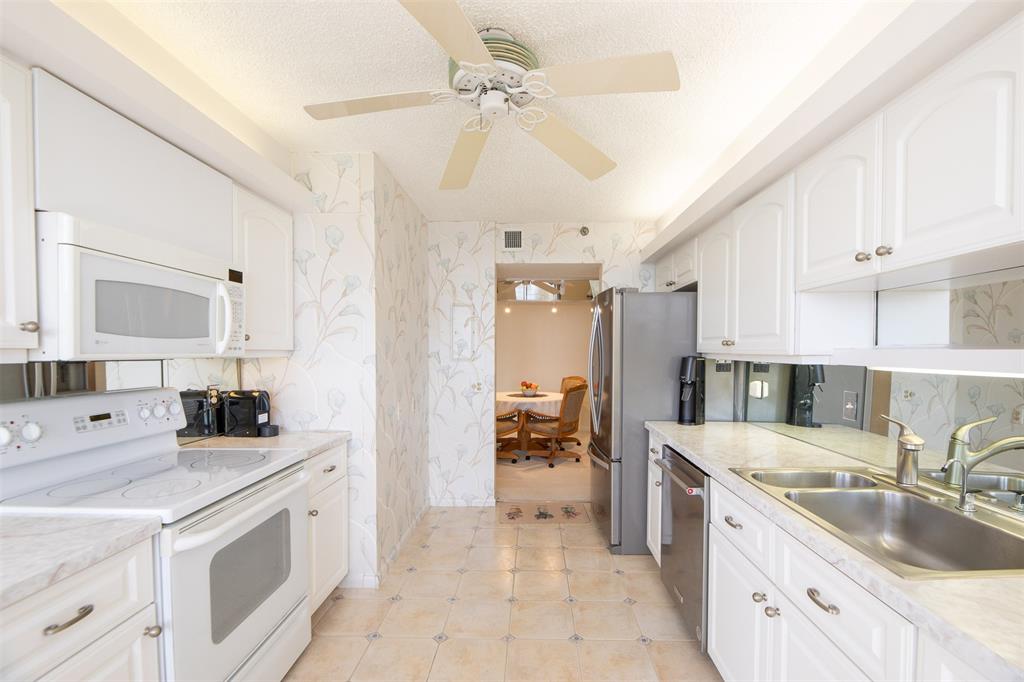 4600 South Ocean Boulevard, Unit 603 Highland Beach, FL 33487 - Photo 11 of 35 a kitchen with a sink stove and cabinets