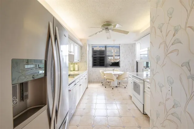 a living room with stainless steel appliances kitchen island granite countertop a sink a stove and white cabinets with wooden floor