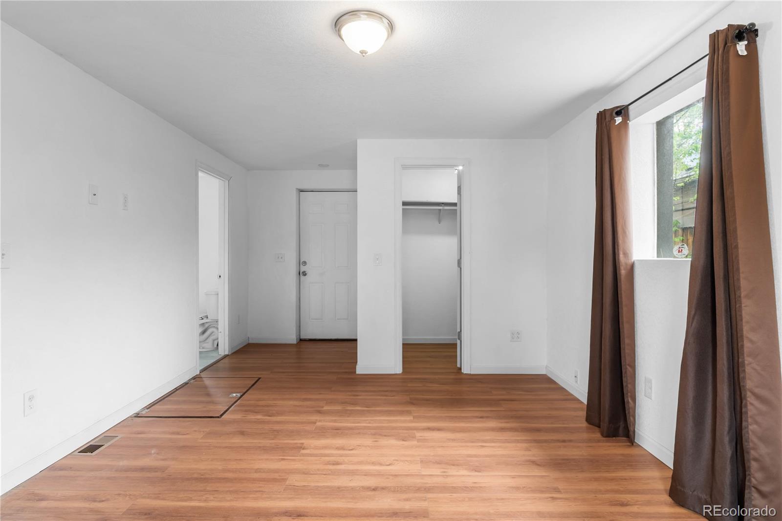 7010 West 44th Avenue Wheat Ridge, CO 80033 - Photo 15 of 31 a view of an empty room with wooden floor and a window