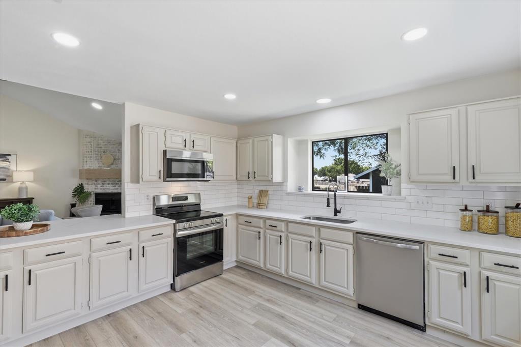 3405 Mill Ridge Street Bedford, TX 76021 - Photo 4 of 32 White shaker cabinetry, light wood-finish flooring, stainless steel appliances, recessed lighting, and a subway tile backsplash