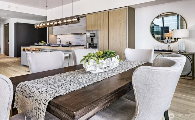 a living room with stainless steel appliances furniture a rug and a kitchen view