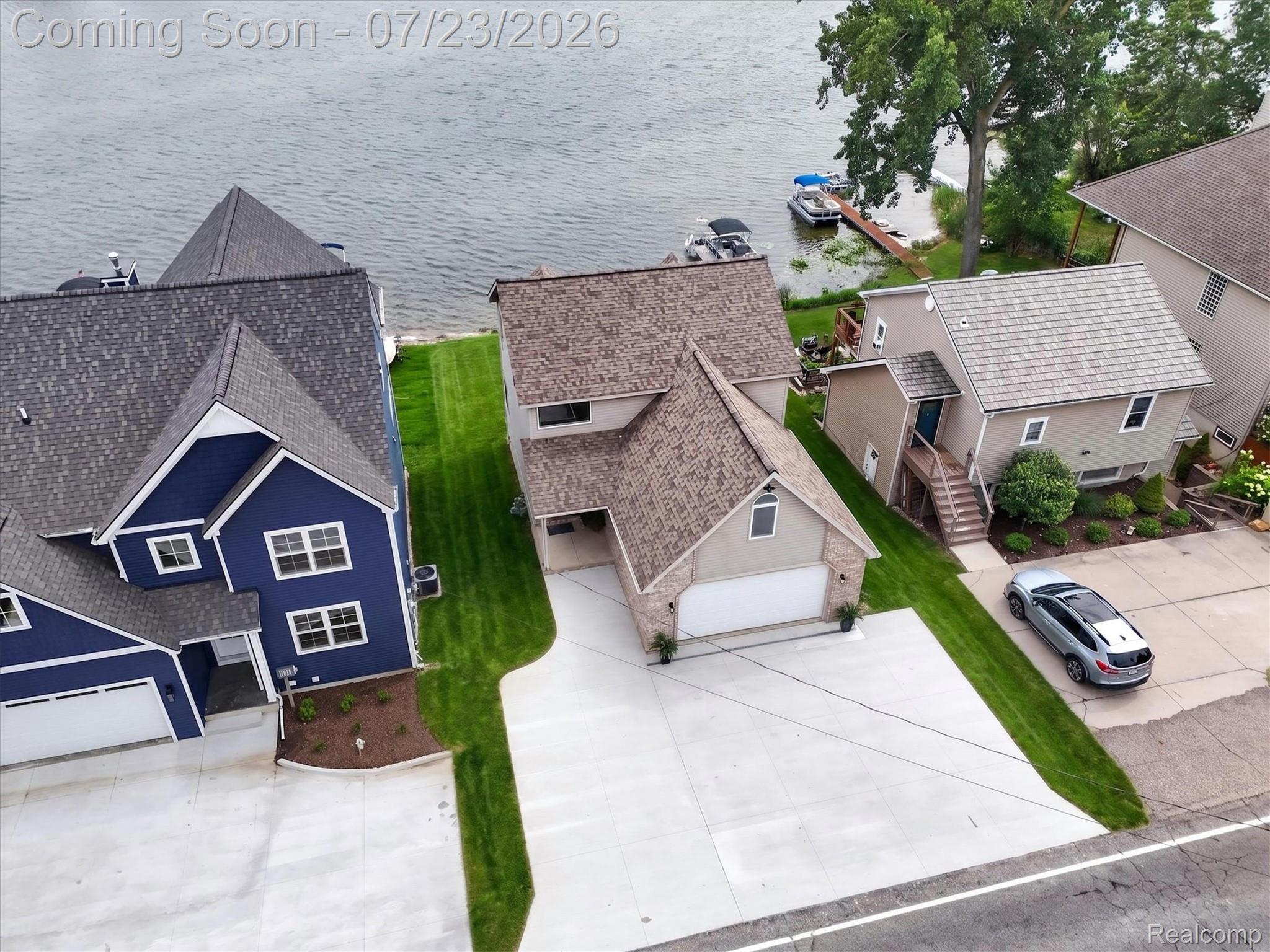 3429 Rolston Road Fenton, MI 48430 - Photo 52 of 62 Waterfront property featuring a two-story residence with a tan exterior, stone accents, and an attached garage