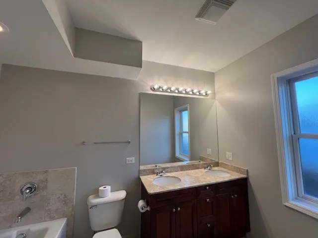 a bathroom with a granite countertop sink a toilet and a mirror